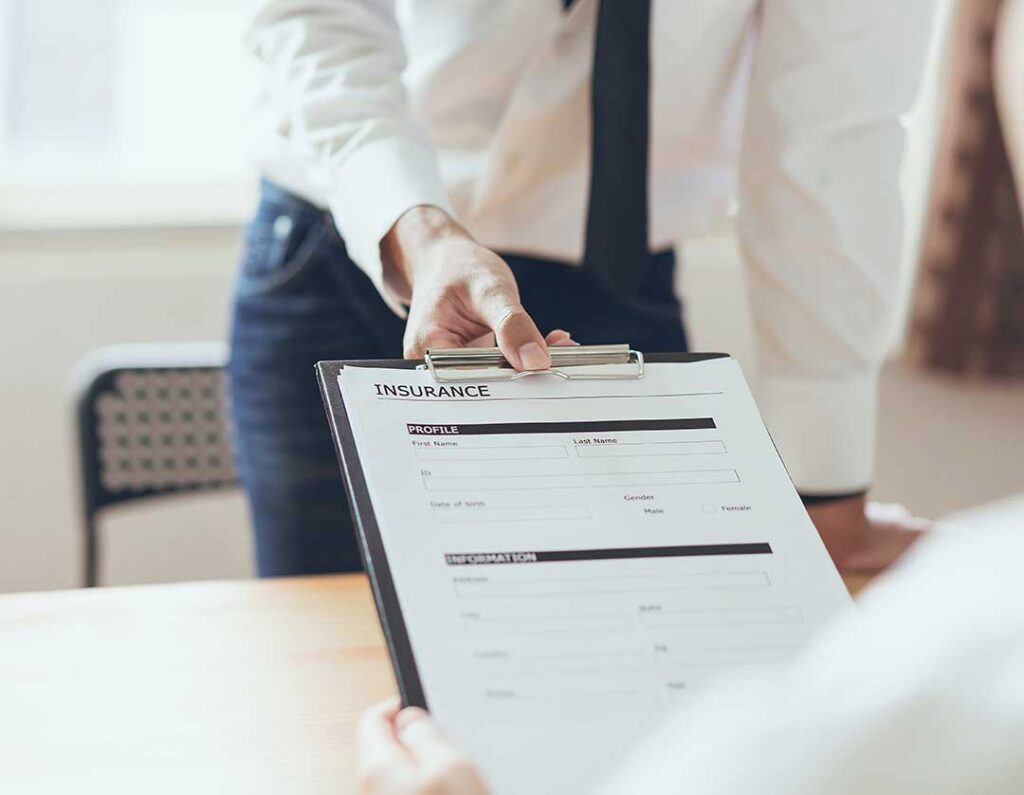 Family reviews insurance documents at a kitchen table beside a home inventory and calculator.